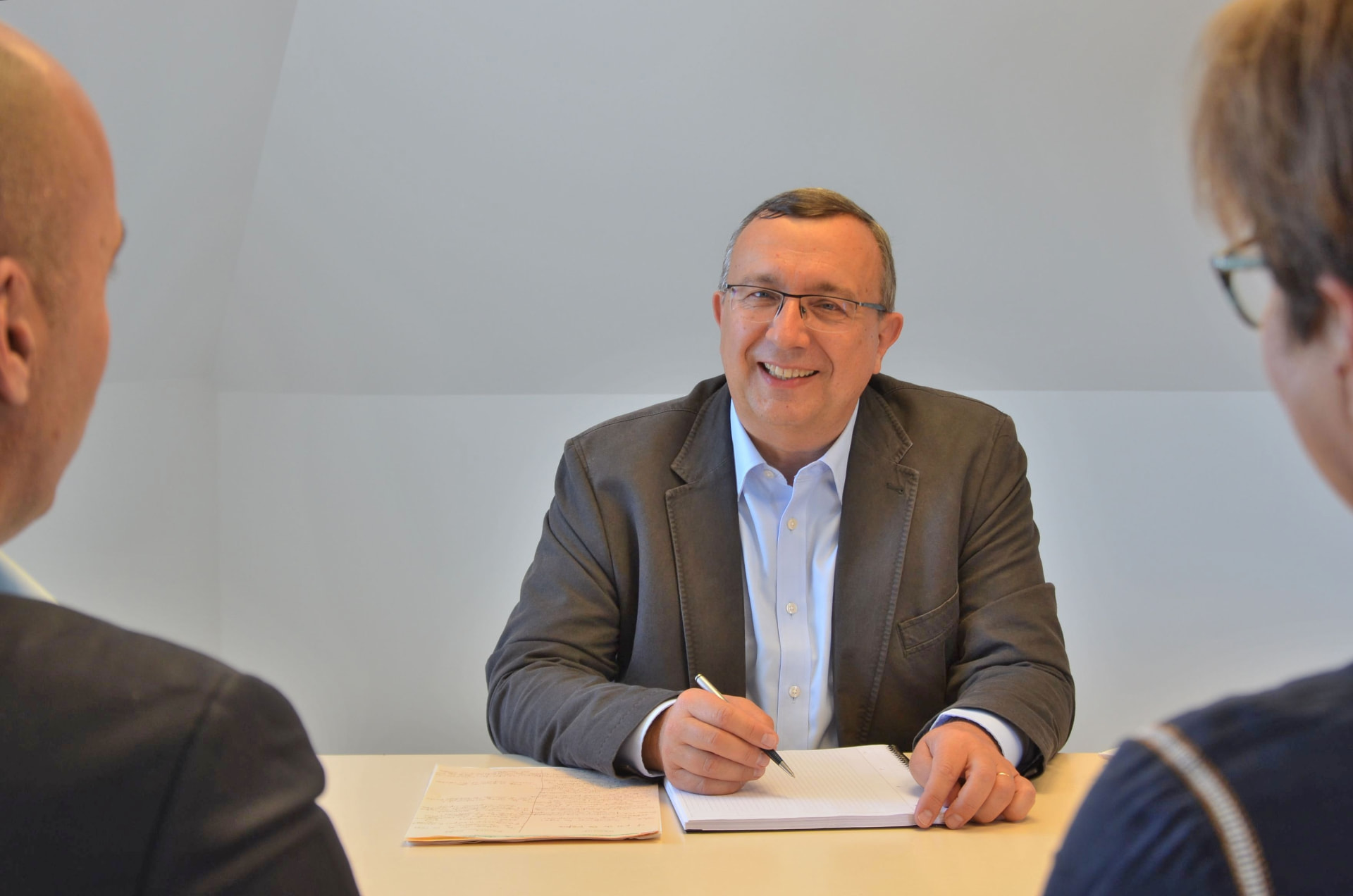 Jean-Michel Poupeau en réunion de travail, prenant des notes face à deux interlocuteurs